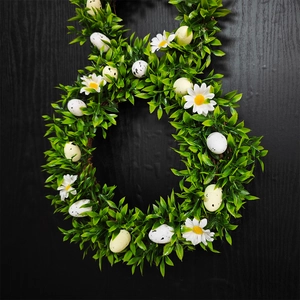 Close-up of Easter bunny wreath with green leaves, white daisies, and speckled eggs on door