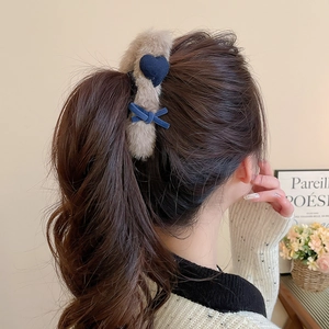 Detail of plush heart claw clip with blue velvet bow shown on woman hair