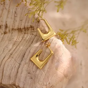 Polished 18K gold stainless steel geometric earrings on a natural wood background