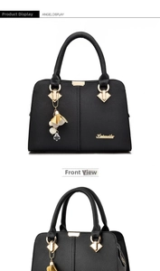 Détail du sac à main en cuir grainé noir avec logo doré et breloque florale élégante