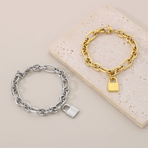 Close-up of gold and silver chunky chain bracelets with metal lock pendants on a stone tray