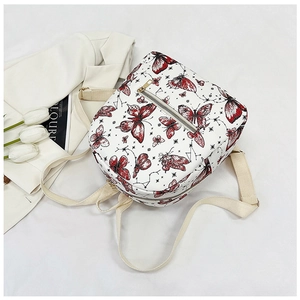 Flat lay of a white backpack with red butterfly prints and stylish tulips decoration