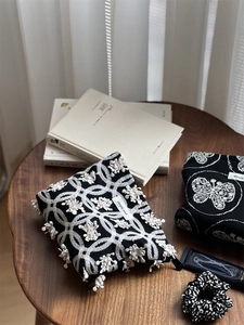 Detail of black canvas makeup bag with exquisite white butterfly and floral embroidery