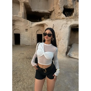 Detailed close-up of white mesh long-sleeved crop top with knot design and sheer texture