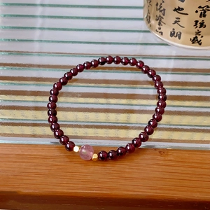 Detail of garnet beaded bracelet with pink strawberry quartz and gold metal spacers
