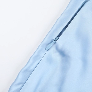 Macro de la fermeture éclair invisible sur robe en satin bleu clair avec texture lisse
