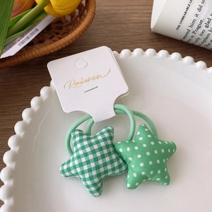 Close-up of green star-shaped hair scrunchies with plaid and polka dot fabric patterns