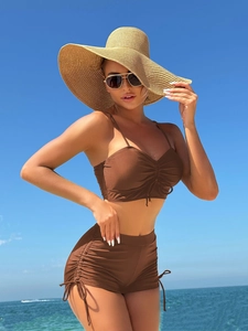 Two-piece brown swimsuit with ruched tank top and high-waisted shorts on beach