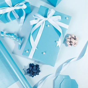 Elegantes hellblaues Geschenkpapier mit Perlglanz, weißem Satinband und Geschenkanhängern