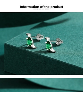 Macro detail of S925 silver penguin earrings with teardrop green crystal stones
