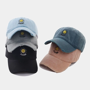 Detail of washed cotton baseball caps with sunshine embroidery and distressed brim texture