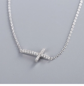 Macro shot of polished silver cross necklace pendant featuring micro-pave diamond setting