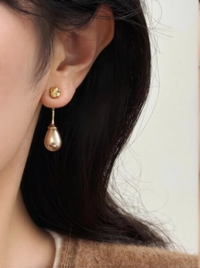 Detail view of champagne water-drop pearl earrings on a model with gold textured studs