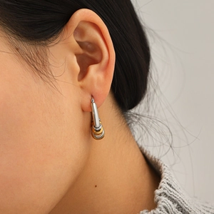 Close-up of two-tone gold and silver stainless steel layered hoop earrings on model