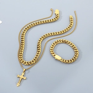 Dettaglio del set collana a doppio strato con croce e bracciale a catena cubana dorata