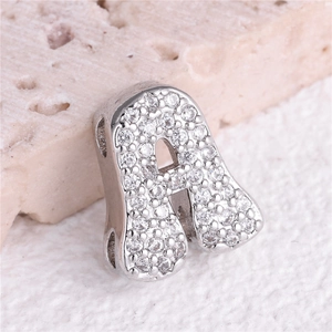Macro shot of silver letter A pendant with clear cubic zirconia pavé on stone background