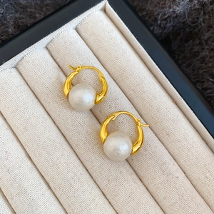 Detailed view of gold-plated round pearl hoop earrings placed in a beige velvet jewelry box