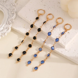 Détail de boucles d'oreilles pendantes avec pierres noires et bleues sur chaîne dorée