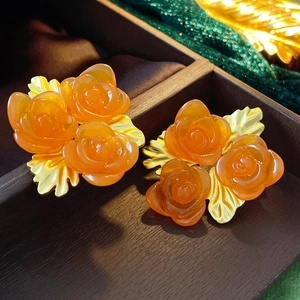 Détail macro de boucles d'oreilles vintage fleurs orange et feuilles dorées en bois