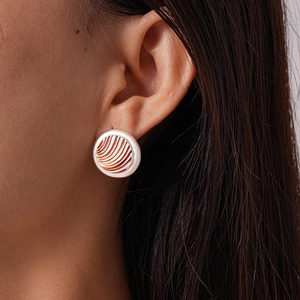 Detailed close-up of a pearl-white round stud earring with orange radial grooves