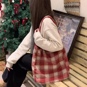 Detail view of large red plaid tote bag worn by model in a festive winter setting