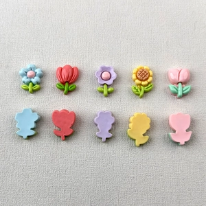 Flat lay of colorful glossy resin tulip and sunflower DIY charms for hair accessories
