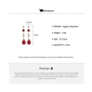 Detail view of red pear-shaped drop earrings with dimensions 6x1.5cm and silver pins