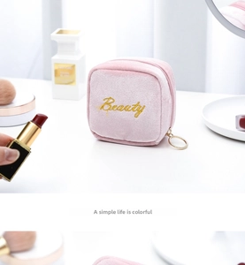 Detail of pink velvet cosmetic bag with gold Beauty embroidery and circular zipper pull