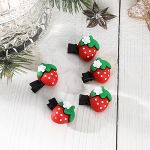Detailed top view of five strawberry hair clips on wood surface for Christmas holiday