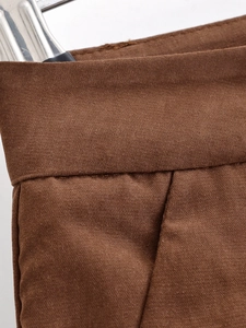 Detailed close-up of dark brown twill fabric with precise stitching on the waistband