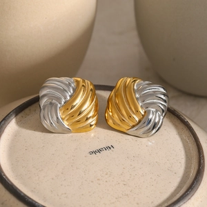 Macro shot of two-tone square twisted earrings with gold and silver metallic texture