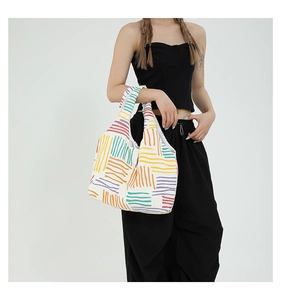 Lifestyle shot of a colorful rainbow line pattern canvas tote bag worn by a model