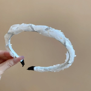 Close-up of white mesh headband with sparkling rhinestones and delicate faux pearls