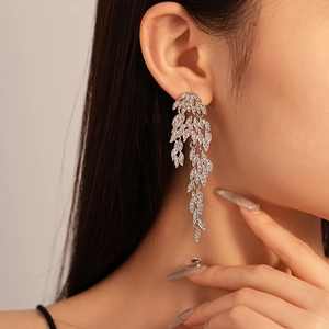 Close-up of sparkling silver leaf tassel earrings with rhinestones on model side profile