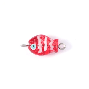 Close-up of a red handmade glass fish pendant with white stripes and blue eyes