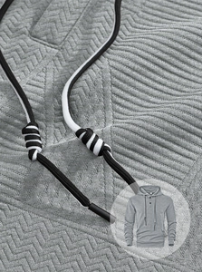 Gros plan d'un sweat à capuche gris avec texture chevrons et détails de cordon rayé