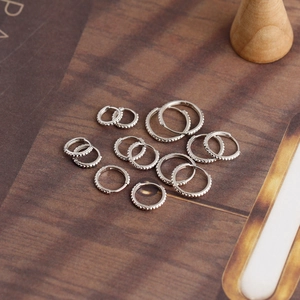 Detailed view of S925 sterling silver milgrain hoop earrings in various sizes on wood surface