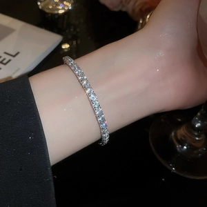 Close-up of a silver tennis bracelet featuring round-cut crystals on a female wrist