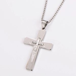 Macro view of silver cross pendant with detailed religious prayer engraving on layered metal