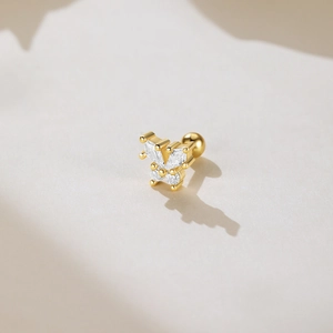 Macro shot of gold butterfly stud earring with cubic zirconia on a soft beige background