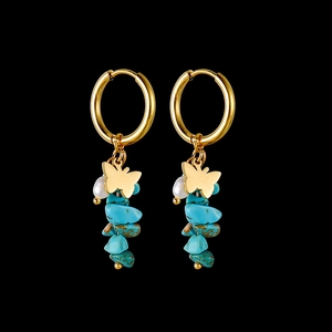 Detail of 14k gold hoop earrings with butterfly charms and natural turquoise stones