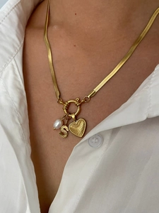 Detailed shot of golden snake chain with pearl, letter S and heart pendant set