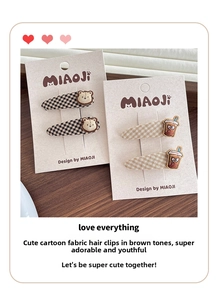 Close-up of fabric hair clips with teddy bear embroidery and plaid patterns on paper card