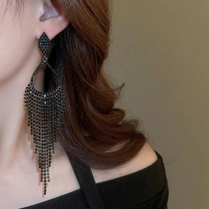 Detail view of long black tassel earrings with sparkling rhinestones on a model