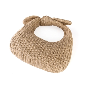 Detail of khaki straw crescent bag featuring an oversized woven bow on the handle