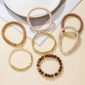 Detail view of 7-piece bohemian heishi bead elastic bracelets with heart charms and gold accents