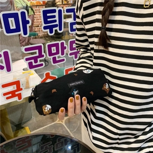 Handheld view of a black canvas pencil case with detailed cat embroidery and zipper