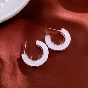 Silver-colored hoop earrings with marble inlay on luxury reddish-brown satin fabric