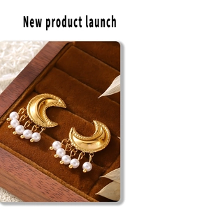 Detail of moon-shaped earrings with pearl tassels in a vintage wooden jewelry box