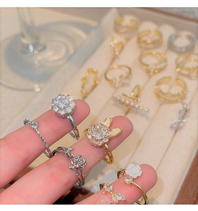 Detailed shot of open rings featuring zircon rabbit and flower designs on a velvet tray